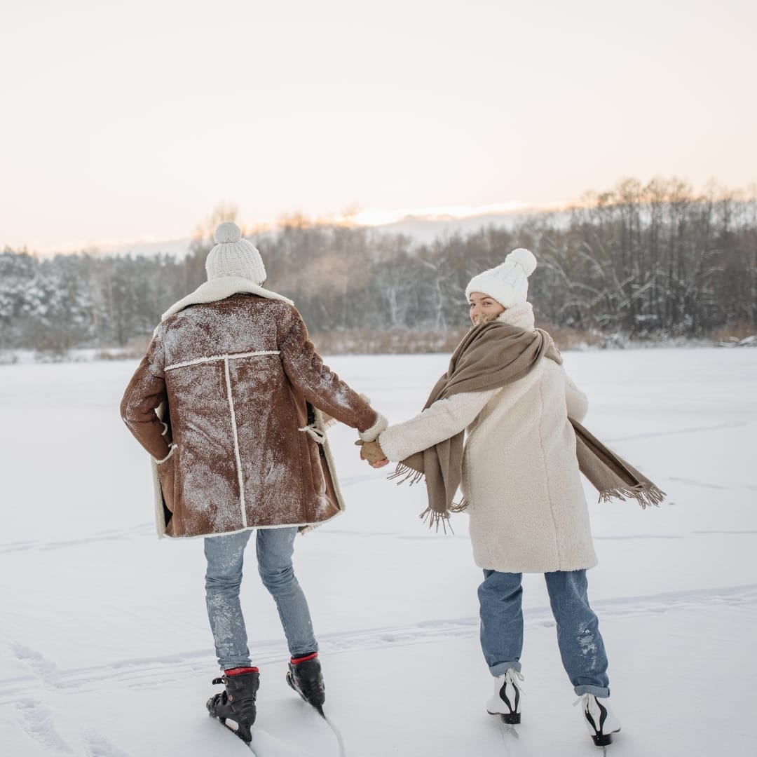 Man och kvinna som åker skridskor på sjön i vinter
