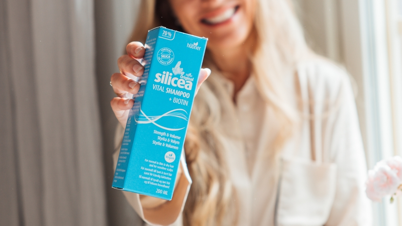 Kvinna som håller förpackningen till Silicea Vital Shampoo