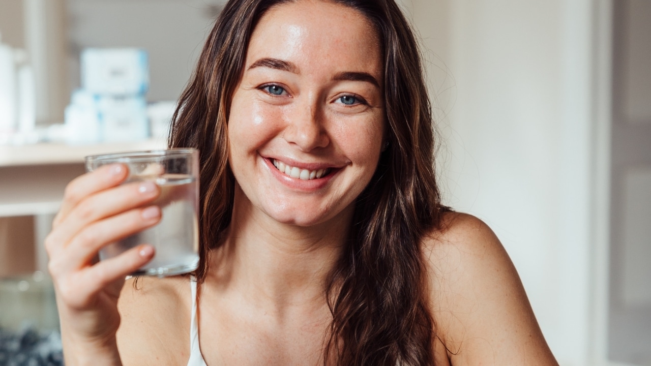 Kvinna håller ett glas med Original Silicea kiselgel blandad med vatten